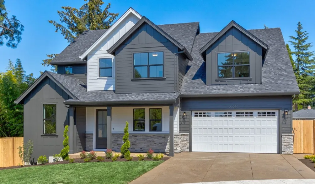 Two-story gray home with white trim, a white garage door, and a landscaped front yard